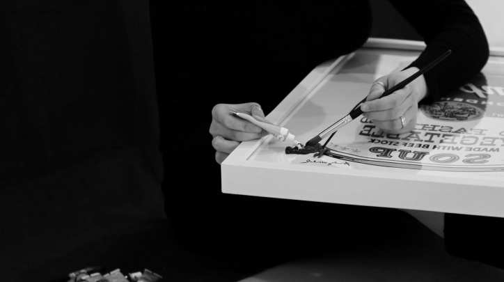 Imatge de l'artista Auri Alós intervenint una peça de l'exposició Robant espai a la paret d'un home ric
